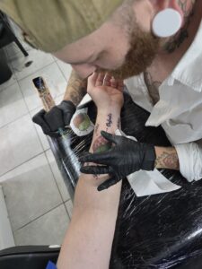 Photo of Jordan Gowins filling in the color on my turtle diagram tattoo
